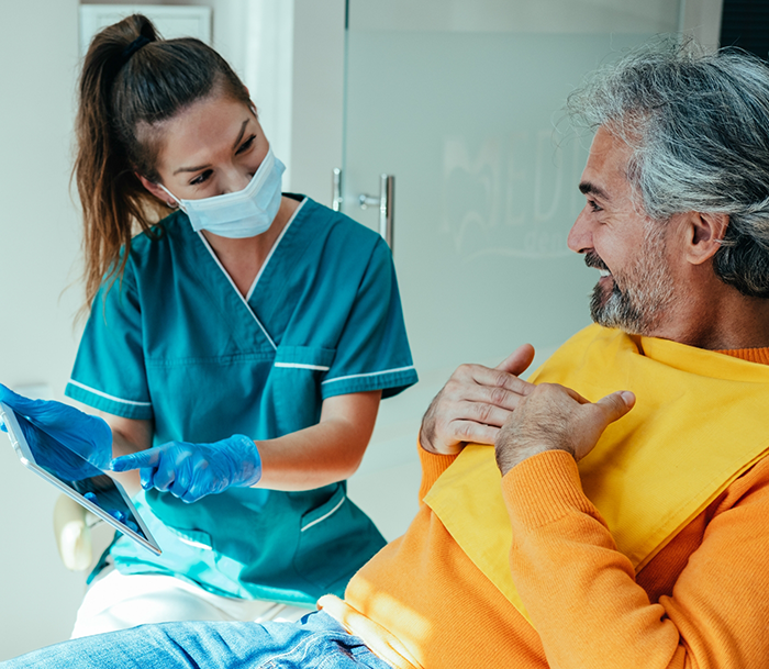Bloomfield endodontist showing a tablet screen to a patient in the treatment chair
