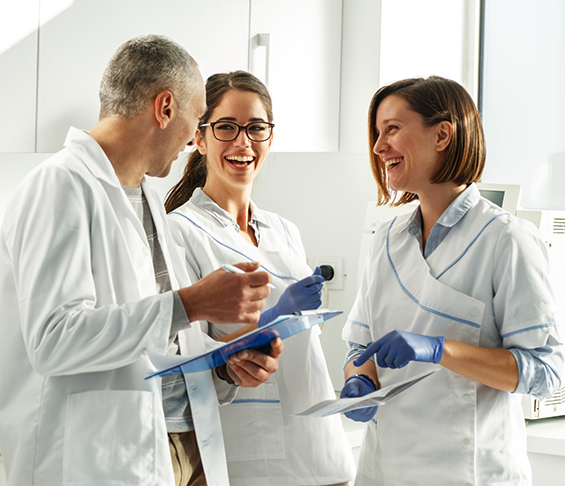Three smiling dentists in white lab coats