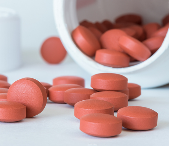 Bottle of red pills spilling out onto a table