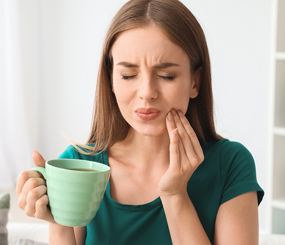 Woman wincing in pain and holding the side of her jaw