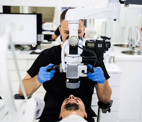 Endodontist using a dental operating microscope to look at a patients teeth