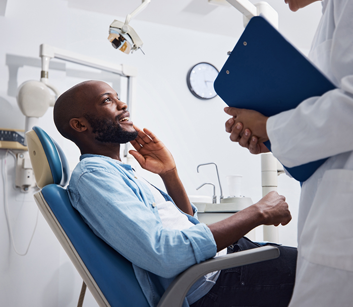 Man touching his face while talking to his emergency dentist in Bloomfield
