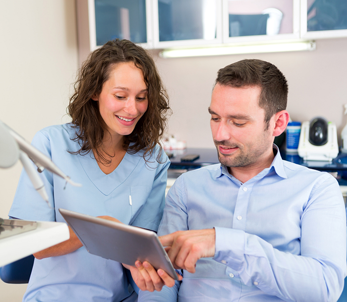Endodontic team member showing a tablet to a patient
