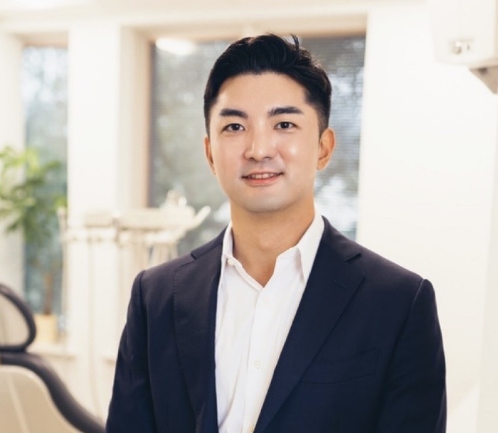 Bloomfield endodontist Doctor Alex Choi smiling in a white dress shirt and a black suit jacket
