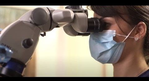 Woman wearing a face mask and looking through a scope lens
